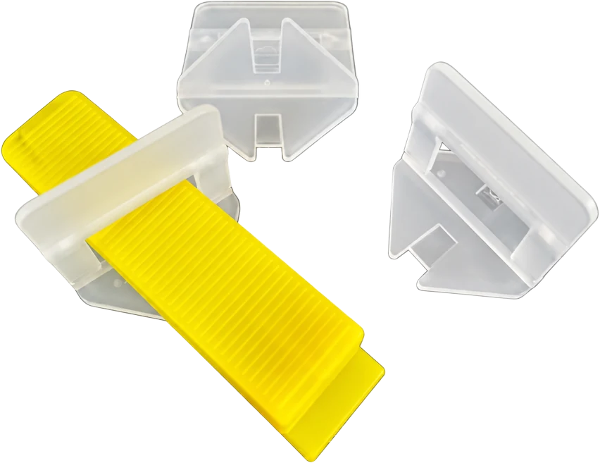 A yellow reusable wedge pushed through the open window of a translucent tile leveling clip, with two empty clips beside it, on a transparent background.